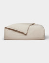 The Cozy Earth Soft-Wash Cotton Duvet Cover, in light beige, is neatly folded with one corner partially flipped over and displayed against a plain white background.|Color:Driftwood