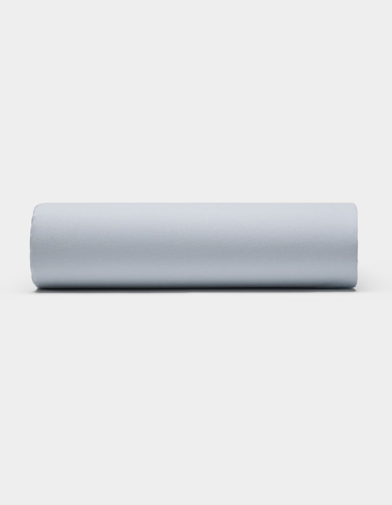A Soft-Wash Cotton Sheet Set by Cozy Earth is displayed on a plain white background, featuring smooth, light gray fabric arranged neatly to showcase its soft texture.