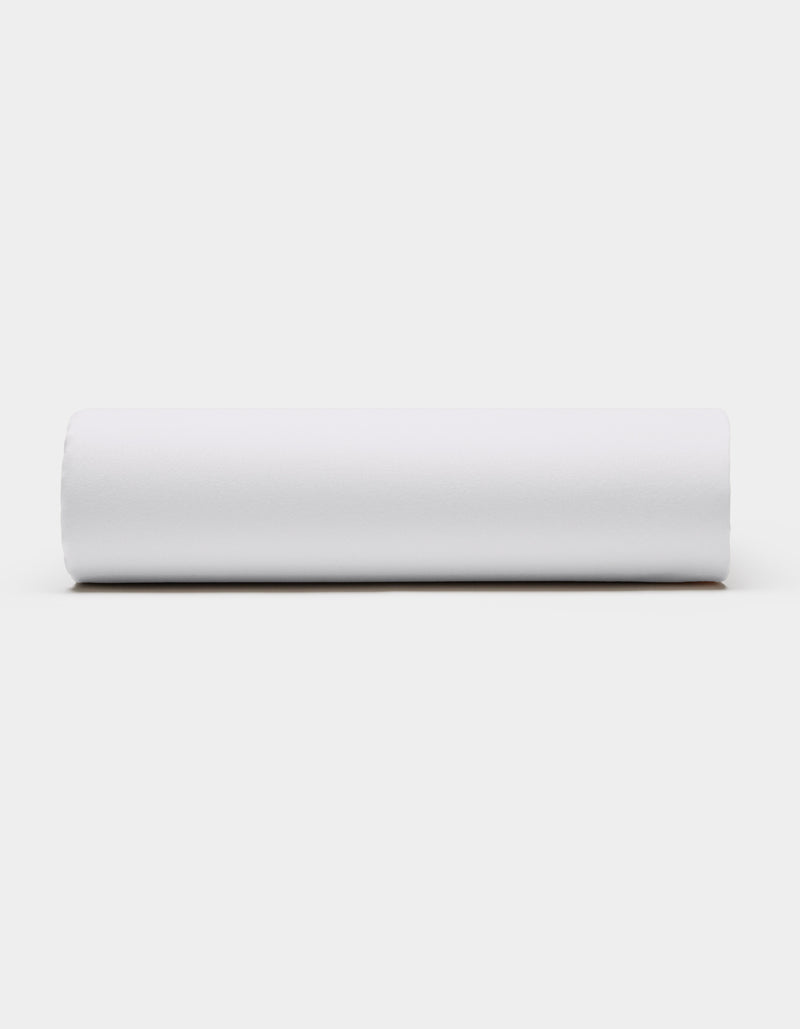 A Soft-Wash Cotton Fitted Sheet by Cozy Earth, in plain white, is displayed horizontally against a light gray background, viewed from the side.