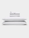 The Cozy Earth Soft-Wash Cotton Sheet Set in white, featuring a flat sheet, fitted sheet, and two pillowcases, is shown neatly stacked against a plain white background.|Color:White