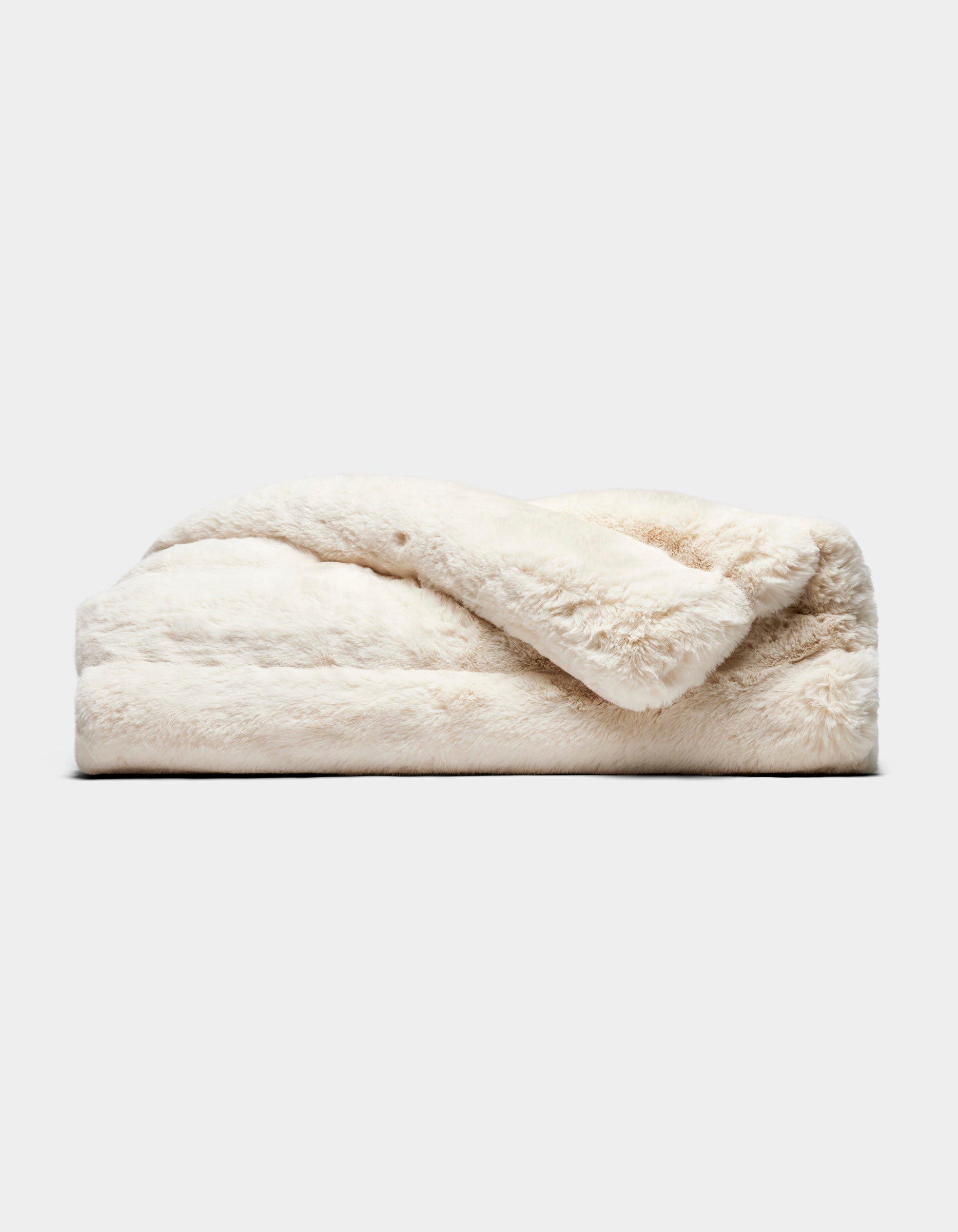 The Cozy Earth Channel Cuddle Blanket, featuring plush off-white faux fur, is neatly folded and displayed against a plain light gray background.
