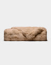 The Double Bubble Cuddle Blanket by Cozy Earth, a rectangular beige faux fur throw, rests on a plain white background with one corner of the plush fur softly folded over the top.|Color:Brandy