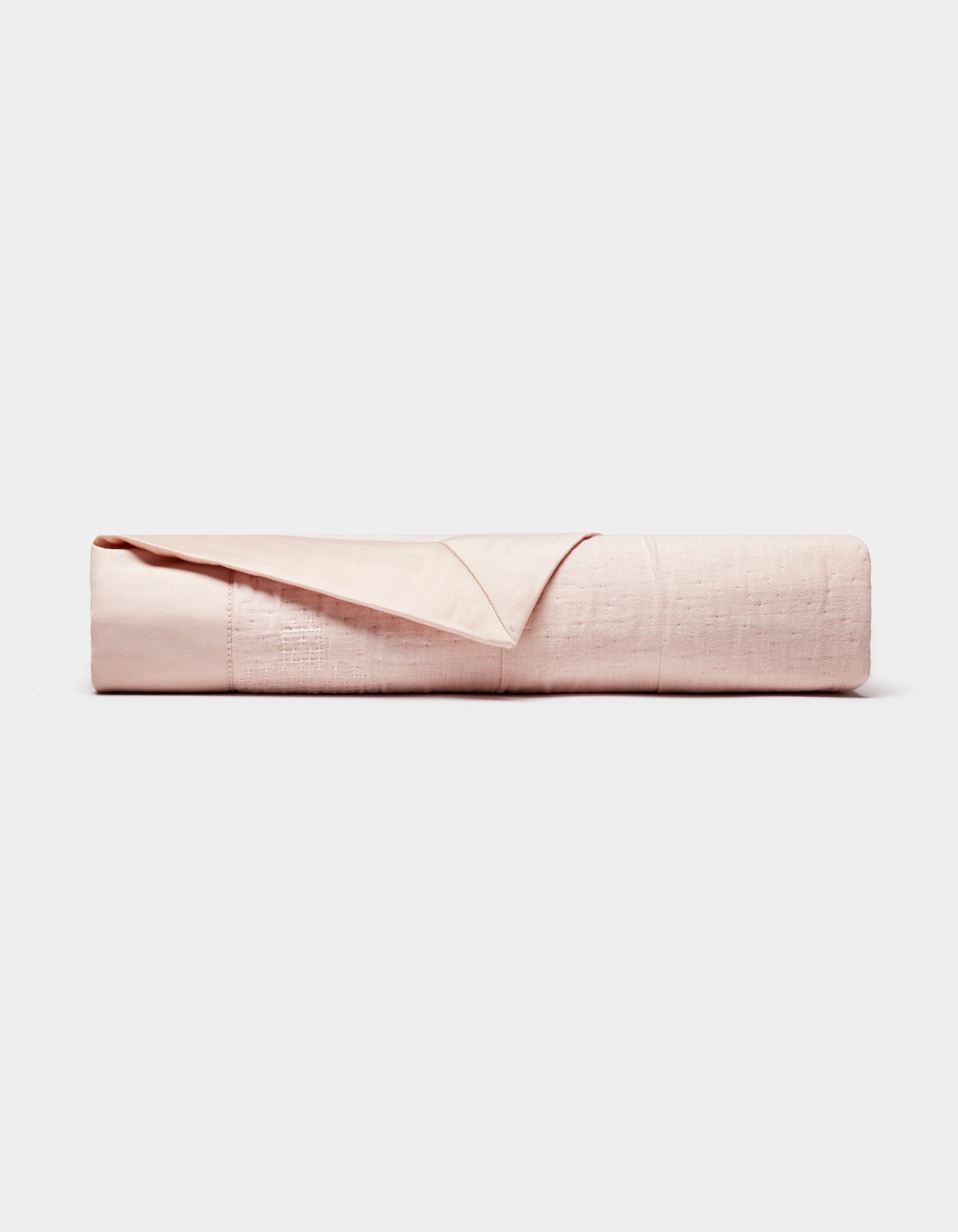 The Cozy Earth Little Bee Matelasse Baby Blanket is neatly folded, showcasing its light pink, textured surface against a plain white background.
