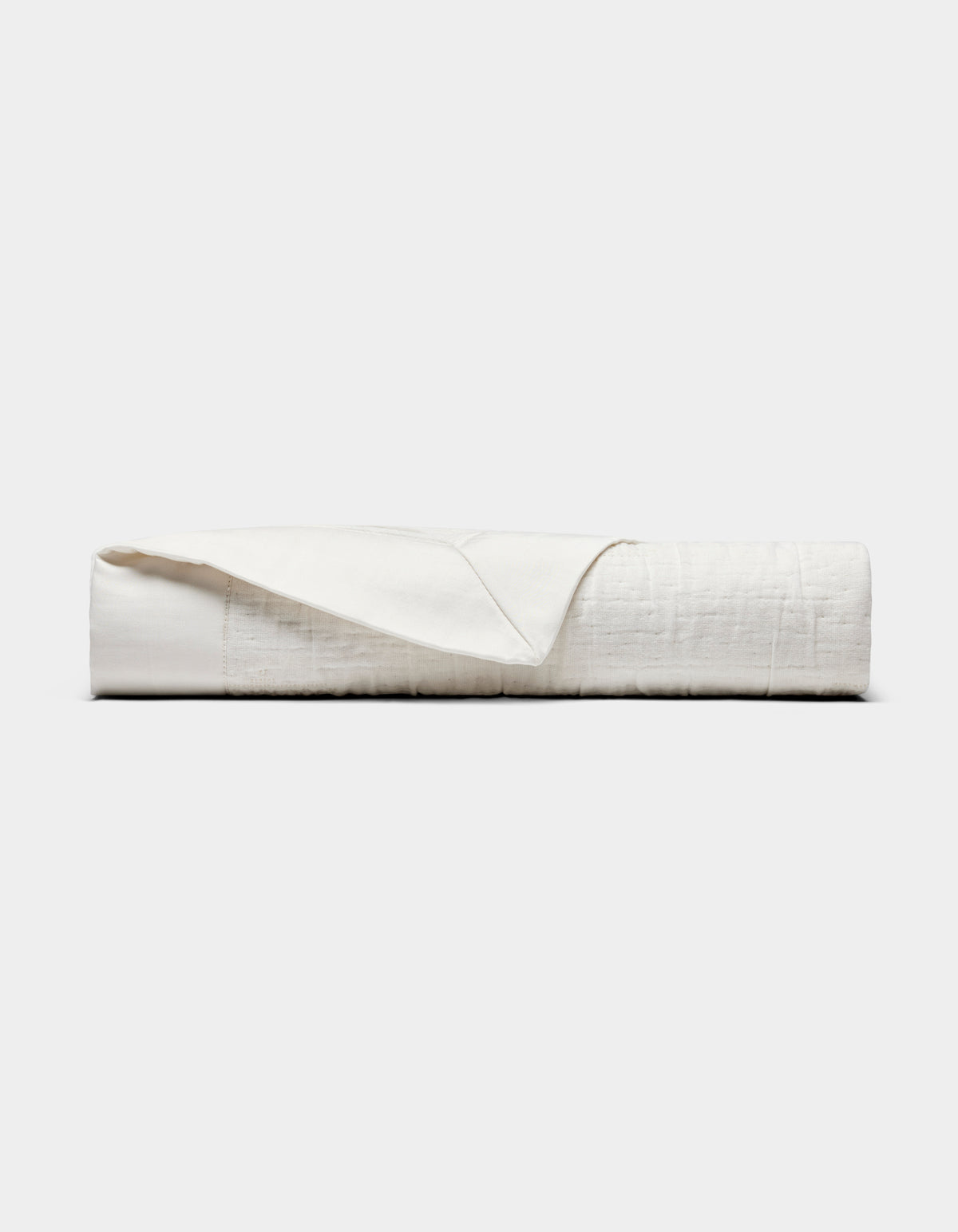The Cozy Earth Little Bee Matelasse Baby Blanket, in white, is neatly folded with one corner partially flipped over and displayed against a plain light gray background.|Color:Sea Salt