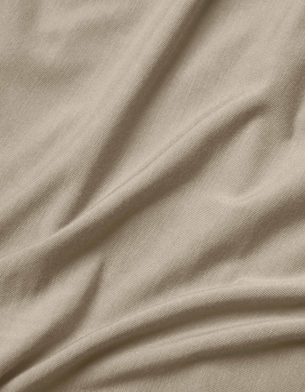 Close-up of Cozy Earth's Bamboo Jersey Flat Sheet in light beige, featuring soft, natural folds, gentle shadows, a smooth texture, and a subtle weave pattern.|Color:Driftwood