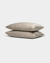 Two Cozy Earth Bamboo Pillowcases in beige, featuring thin horizontal white stripes, are stacked neatly against a plain light gray background.|Color:Classic Stripe in Ebony