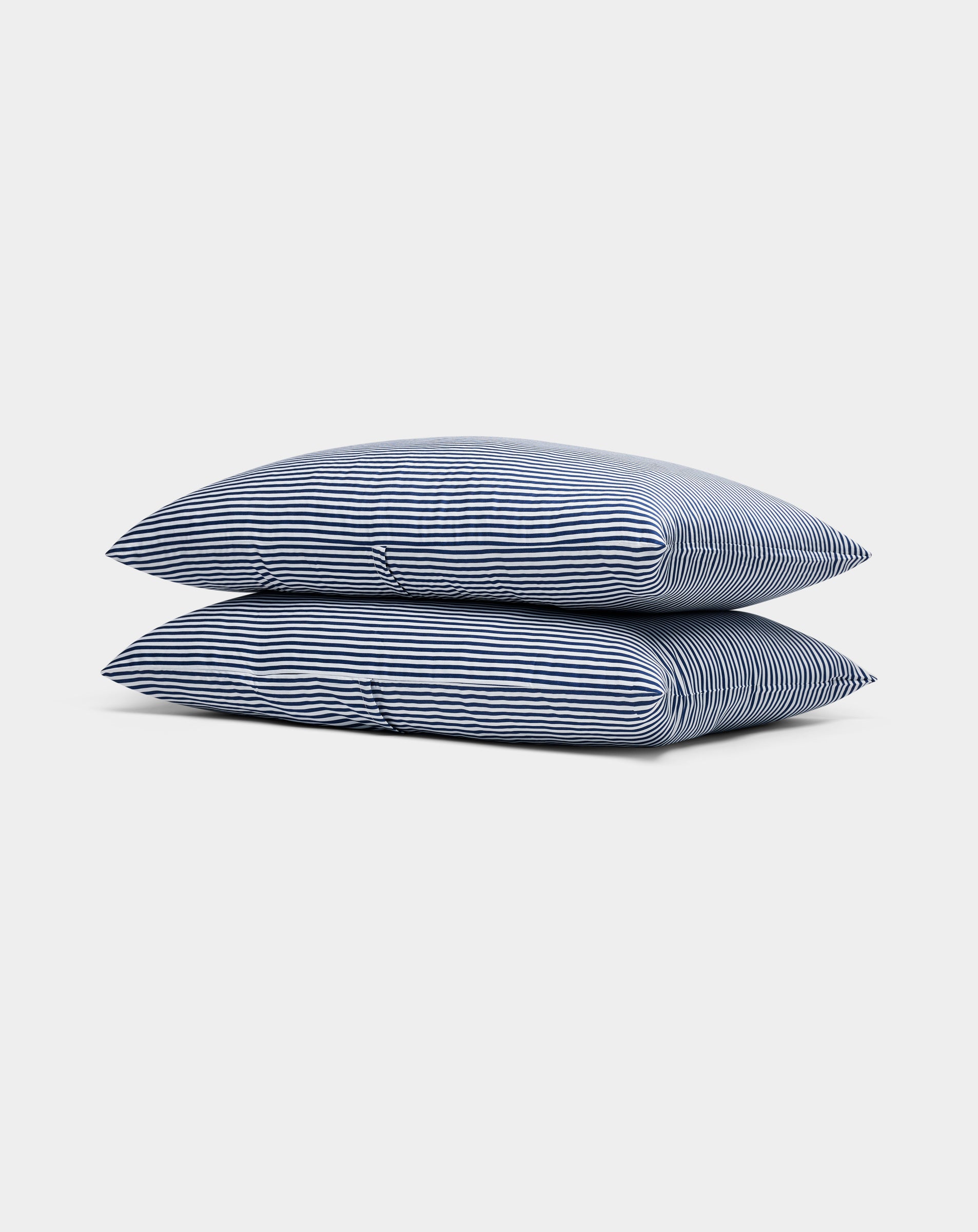 Two Cozy Earth Bamboo Pillowcases, blue-and-white striped, are stacked neatly against a plain white background.|Color:Classic Stripe in Pacific