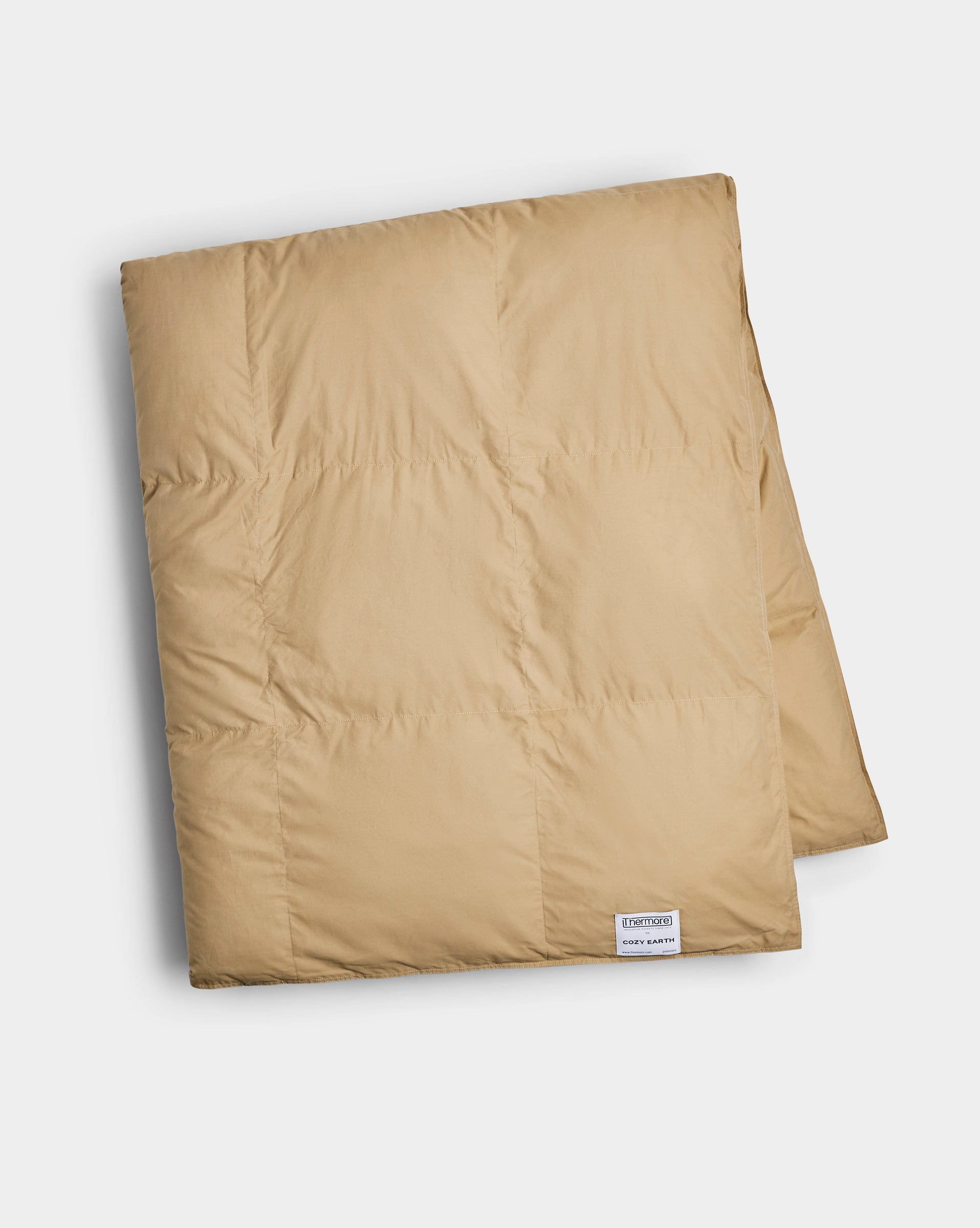 The Cozy Earth Down Alternative Throw is a neatly folded, light brown quilted blanket featuring a small white tag in one corner, displayed on a plain white background.