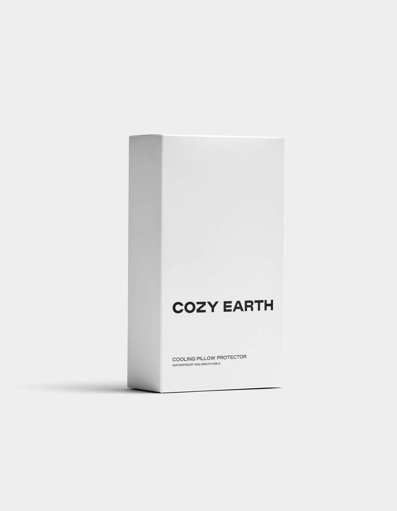 A white rectangular box displays "Cozy Earth" in bold black letters and "Cooling Pillow Protector" underneath, set against a plain light background.