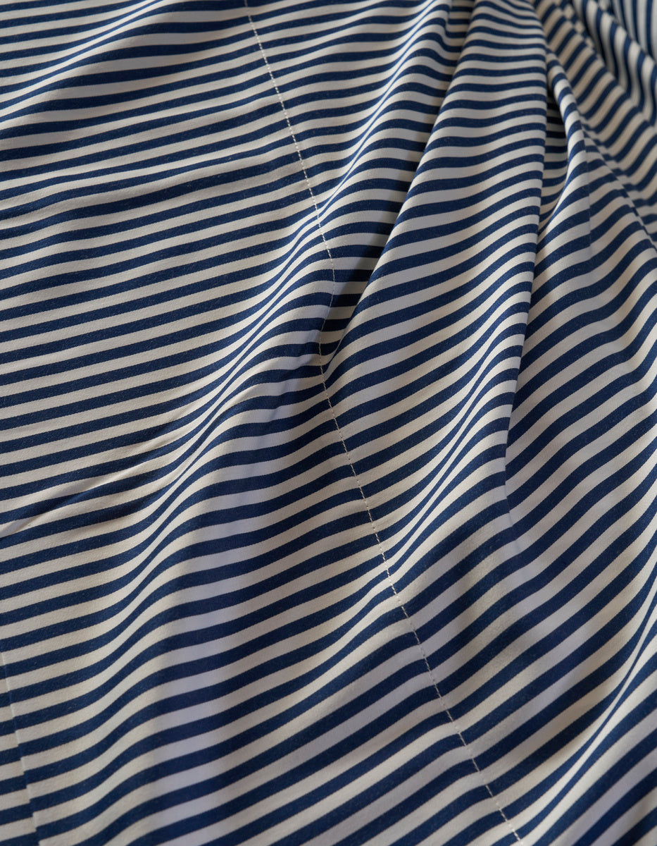 A close-up of the Cozy Earth Bamboo Duvet Cover shows thin, evenly spaced navy blue and white horizontal stripes with visible stitching and gentle folds.