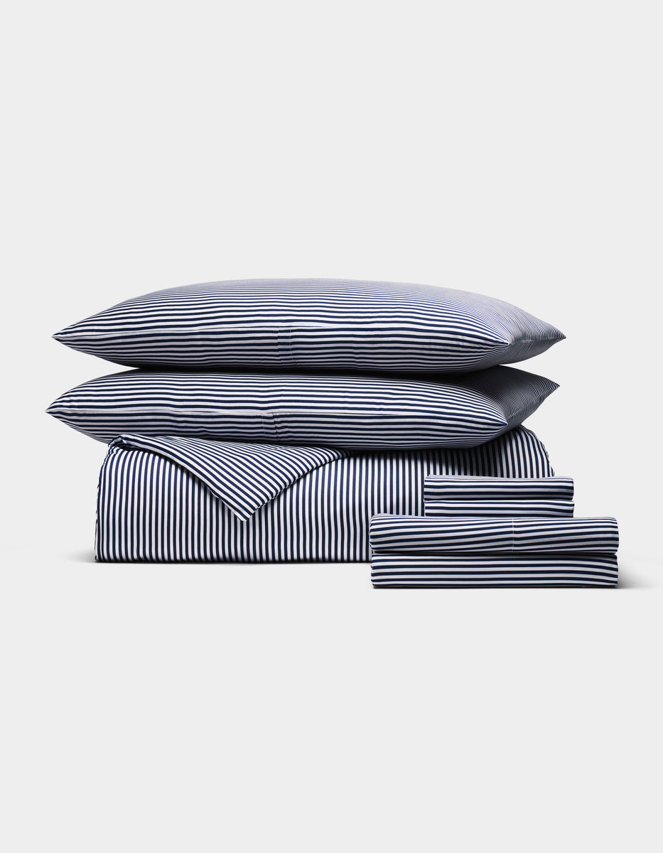 The Cozy Earth Bamboo Bedding Ultimate Bundle, featuring navy blue and white stripes, includes a duvet, sheet, two pillows, and two pillowcases, all neatly arranged on a plain white background.|Color:Classic Stripe in Pacific