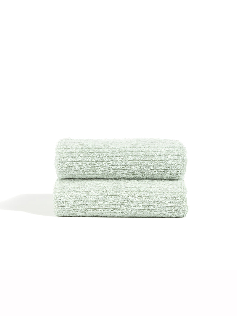 Two Ribbed Terry Hand Towels by Cozy Earth, neatly folded and stacked, are displayed against a plain white background.