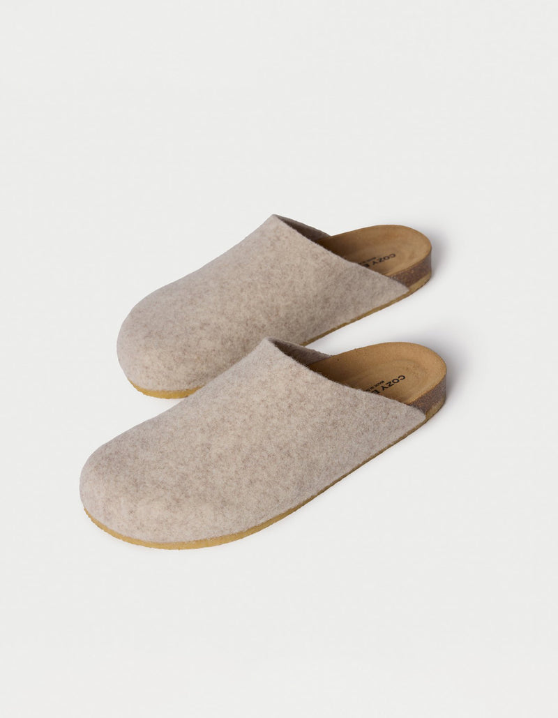 The Lakehouse Clog by Cozy Earth are beige woolen slip-on slippers with a cork sole, viewed from above. They feature a minimalist design perfect for indoor use against a light cream background.