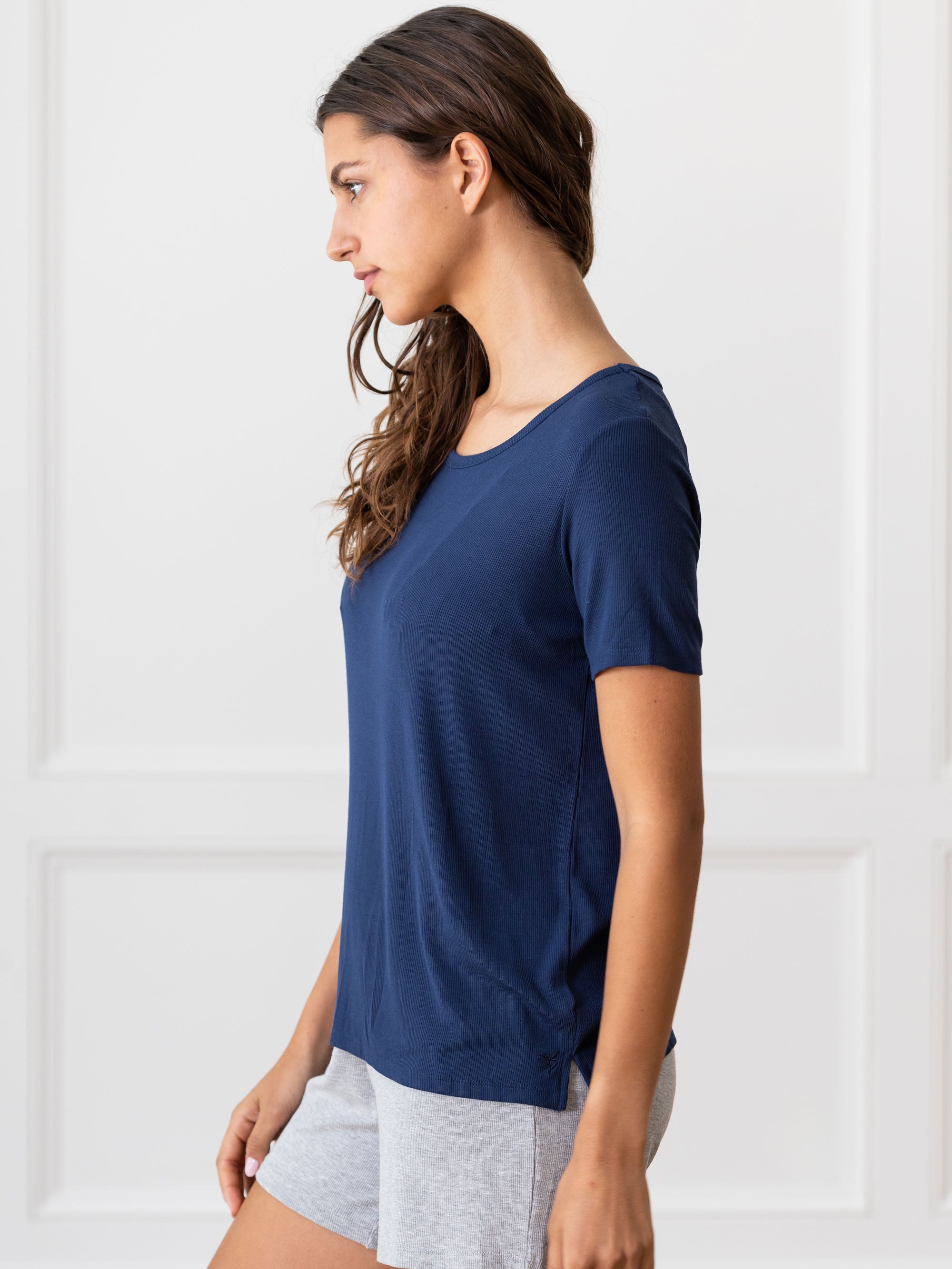 Woman wearing a blue Cozy Earth Rib Knit Short Sleeve Lounge Top and gray shorts against a white background 