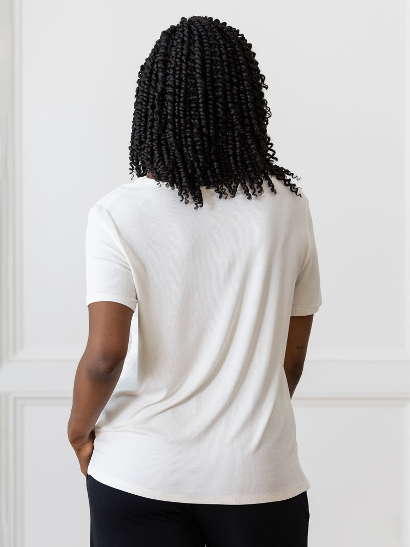 Woman wearing a white Cozy Earth Rib Knit Short Sleeve Lounge Top and black shorts against a white background