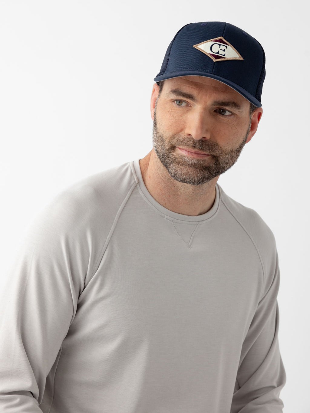 Man wearing navy diamond mesh trucker hat looking to the side 
