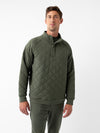 A person stands against a plain white background, donning the Men's Ultra-Soft Bamboo Quilted Snap Pullover from Cozy Earth. The green pullover features a high collar and snap-button closure. The individual, with short light brown hair, looks directly at the camera with a relaxed and confident posture. |Color:Olive