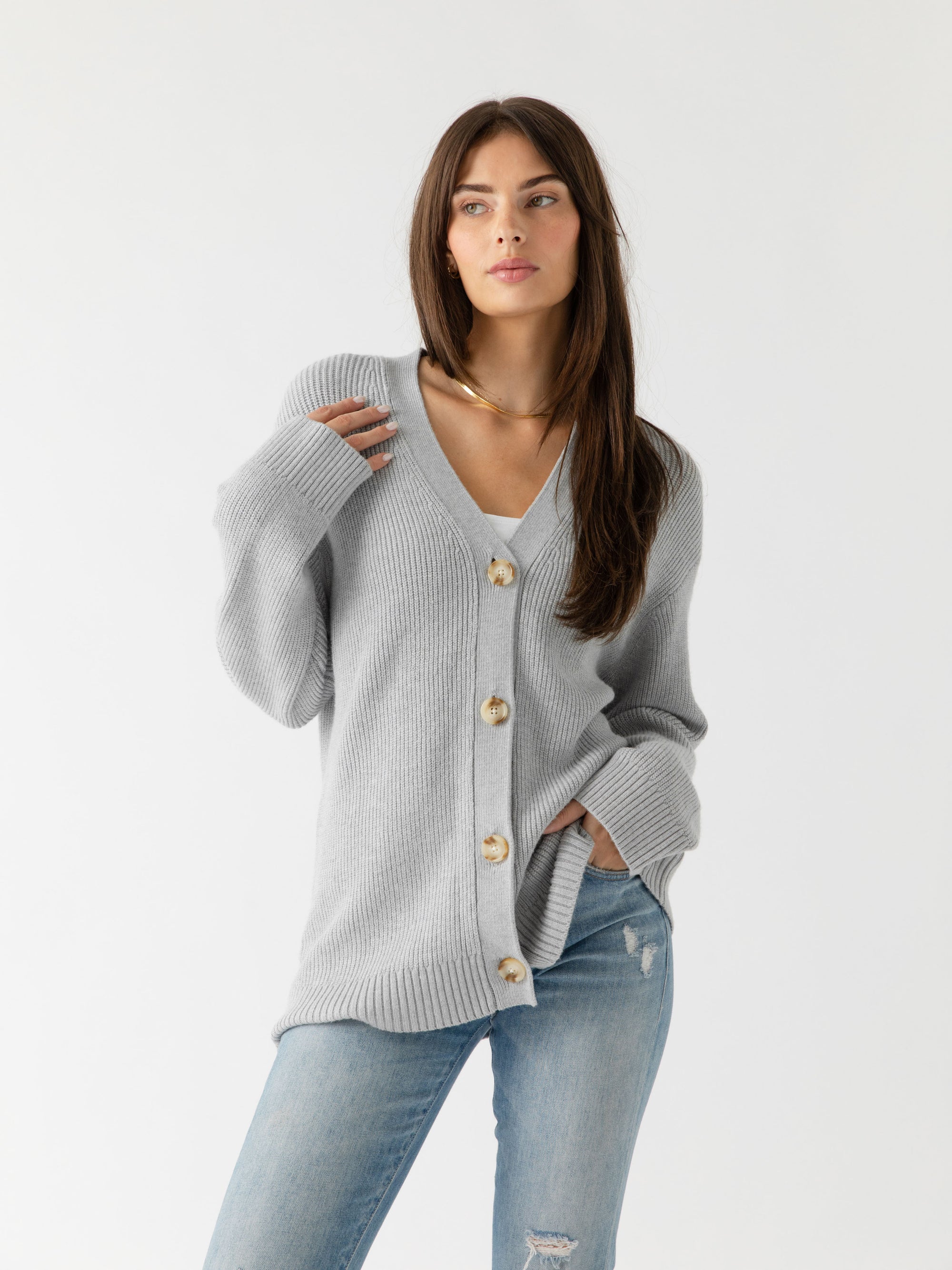 A woman wearing Cozy Earth Classic Cardigan in grey stands in front of a white background 