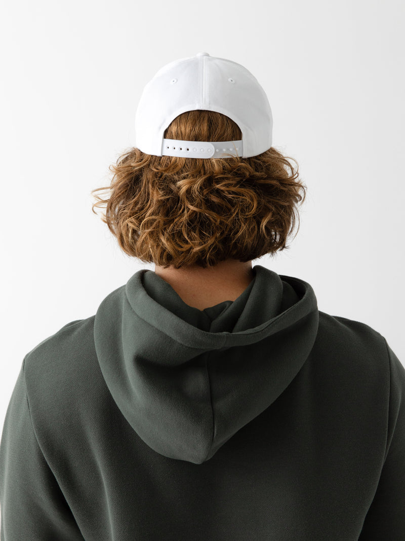 A man facing backwards wearing a White cap on a white background
