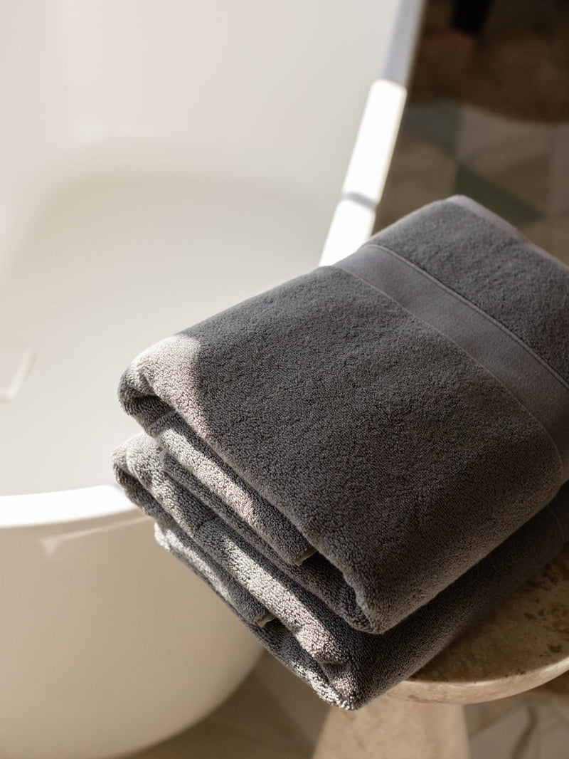 Folded luxe bath sheets next to bathtub