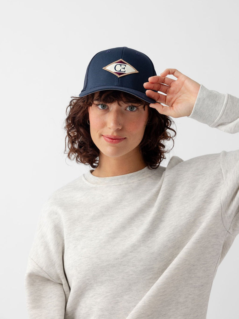 Woman wearing navy diamond mesh trucker hat looking at the camera