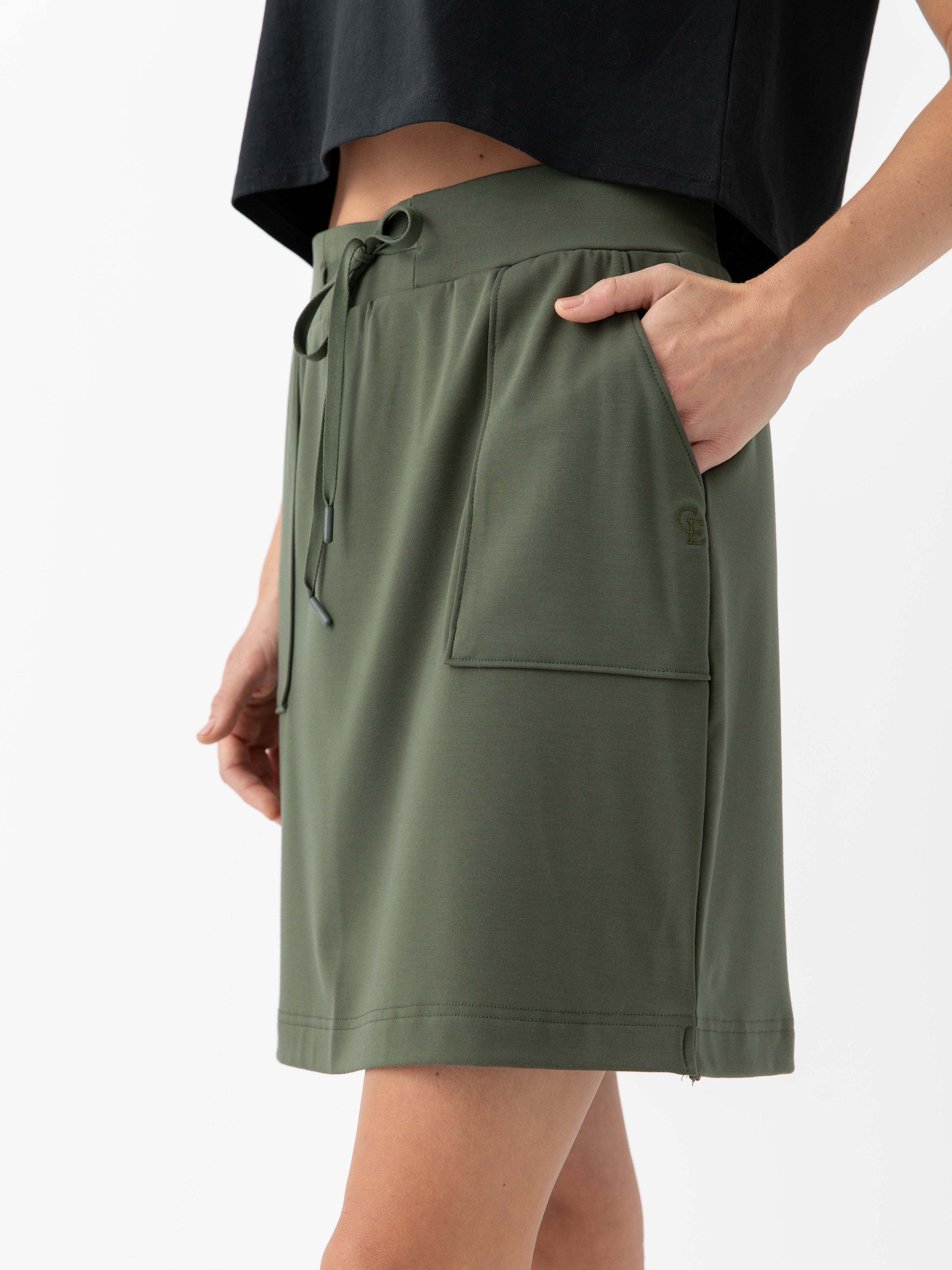 Person wearing a Cozy Earth Brushed Bamboo Patch Pocket Skirt in green on a white background |Color:Olive