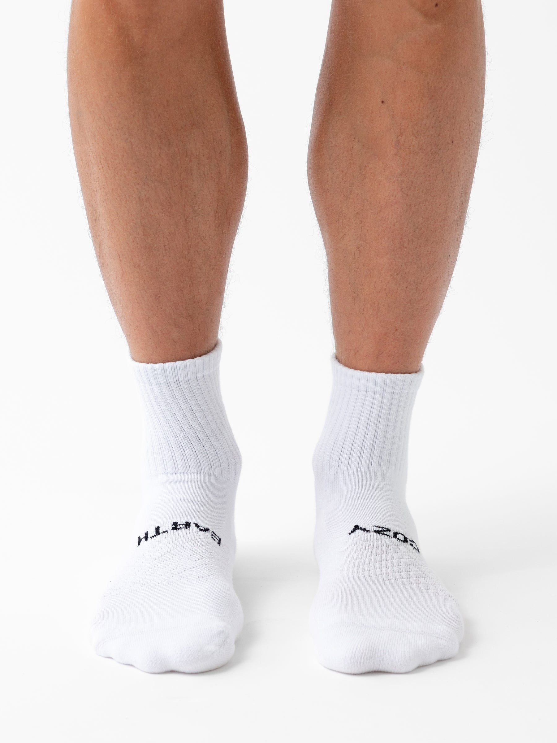 A person wearing Cozy Earth Essential Quarter Sock 8-Pack stands on a white background, with only their lower legs and feet visible. 