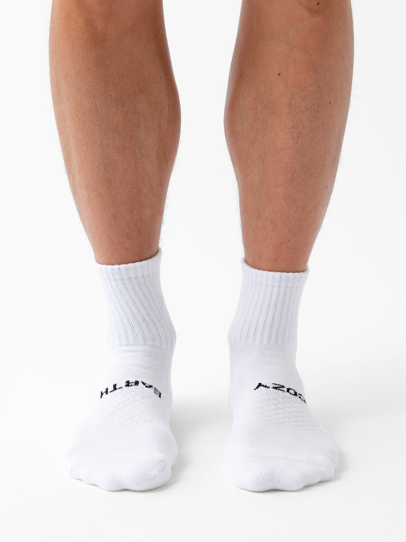 A person wearing Cozy Earth Essential Quarter Sock 8-Pack stands on a white background, with only their lower legs and feet visible.