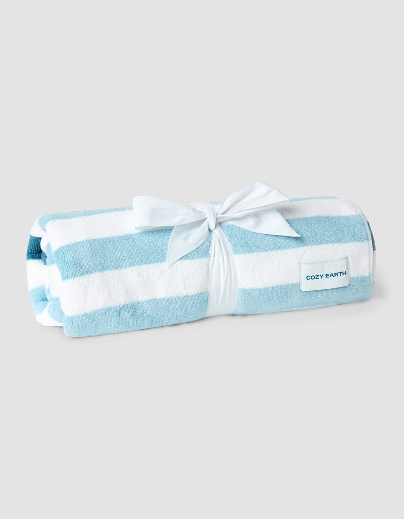 The Cozy Earth Classic Stripe Resort Towel, rolled up and tied with a white ribbon, has blue and white stripes plus a "Cozy Earth" label, displayed on a light gray background.