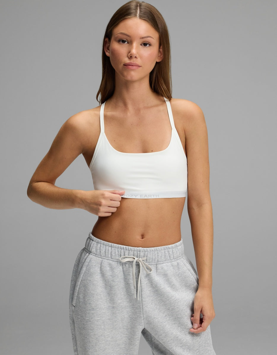 A woman wearing a white Cozy Earth Women’s Balance Bra with a branded elastic band and grey sweatpants.