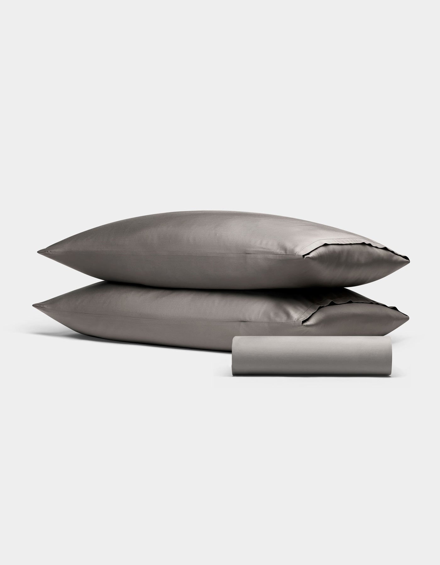 The Bamboo Bedding Basic Bundle by Cozy Earth, featuring two gray pillows stacked and a folded gray bedsheet in front, is showcased against a plain white background.