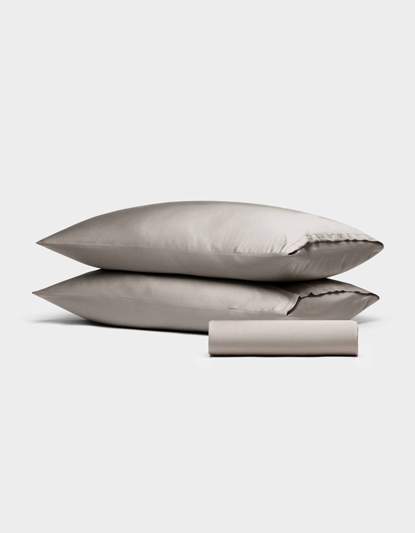 The Cozy Earth Bamboo Bedding Basic Bundle features two stacked beige pillows and a neatly rolled matching beige sheet, all set against a plain white background.|Color:Dove Grey
