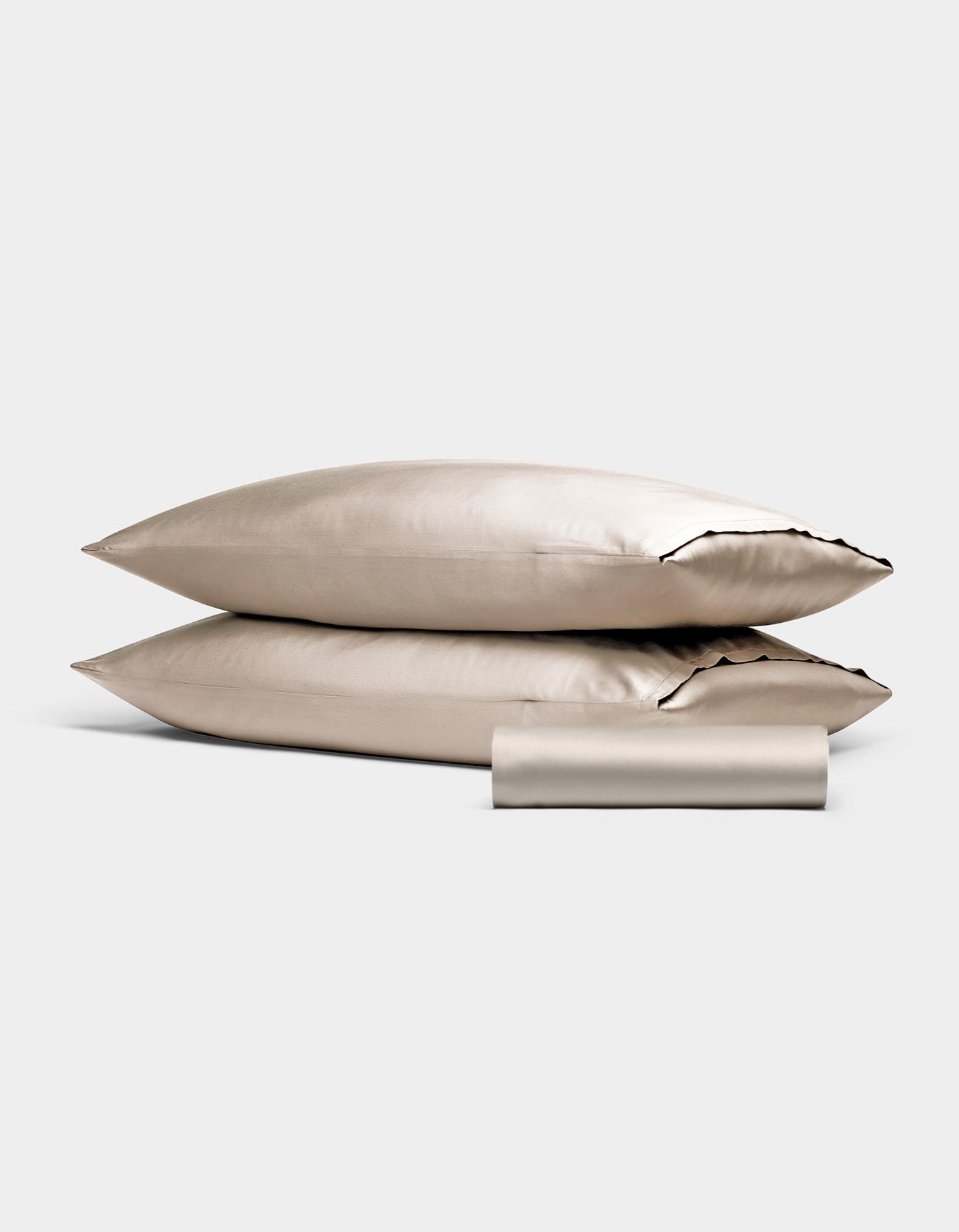 Two Bamboo Bedding Basic Bundle pillowcases by Cozy Earth, in light beige, are stacked with a matching folded sleep mask in front, all set against a plain light gray background.|Color:Driftwood