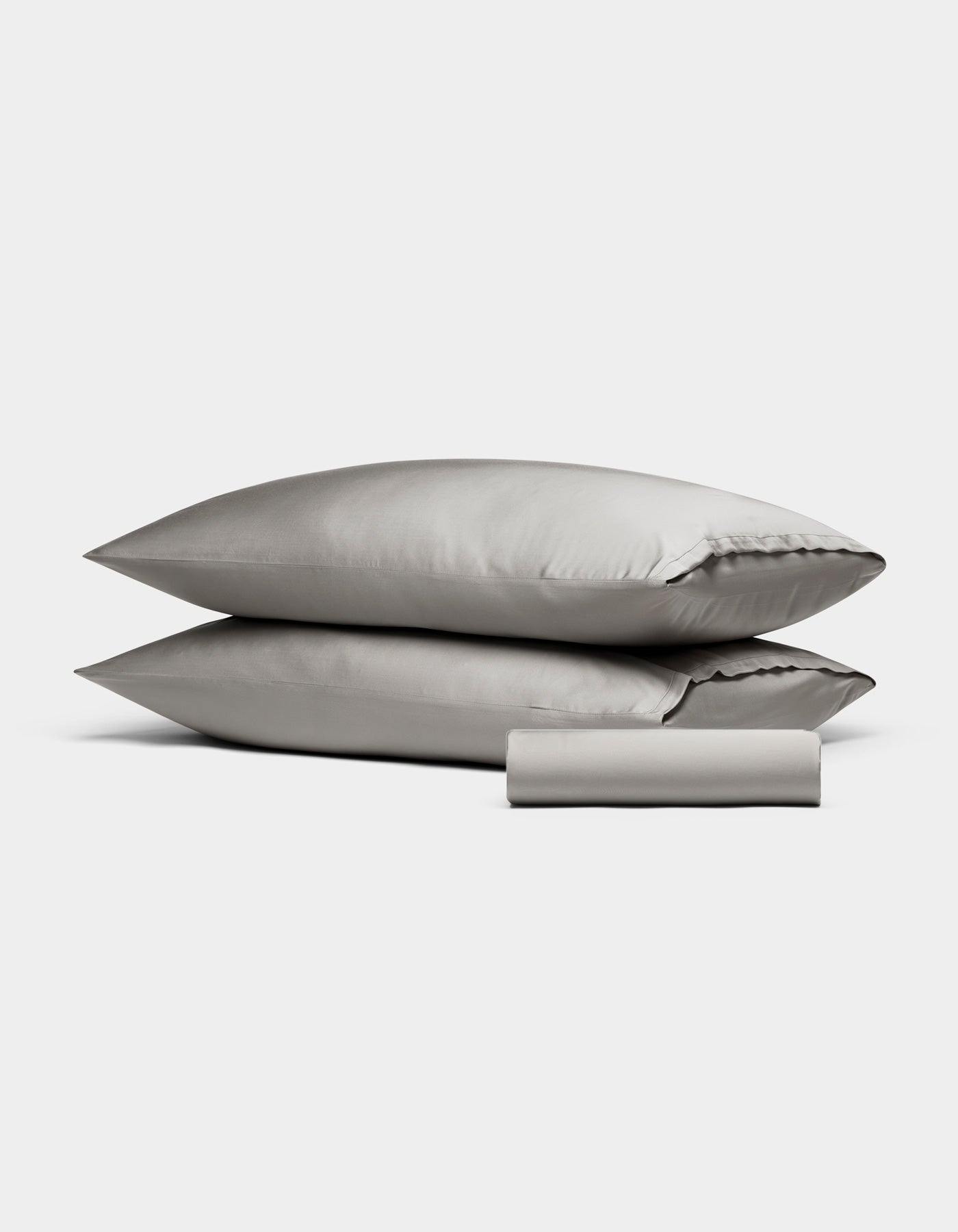 The Cozy Earth Bamboo Bedding Basic Bundle features two light gray pillowcases stacked together with a matching folded bedsheet in front, all displayed against a plain white background.