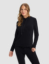 A woman with long, wavy hair wears the Cozy Earth Women's Brushed Bamboo Hoodie in black, posing against a plain light gray background.|Color:Black