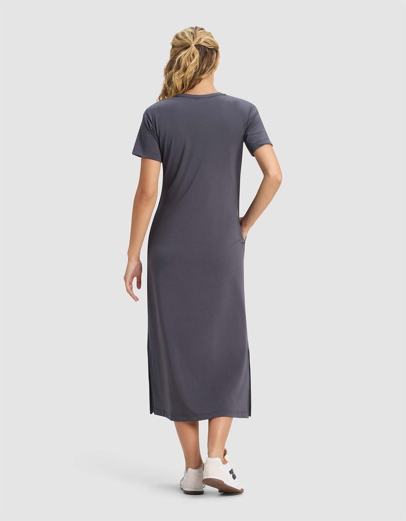 A woman with wavy blonde hair wears a Cozy Earth Women's Brushed Bamboo Midi Dress in gray and white shoes, standing with her back to the camera against a plain light background.