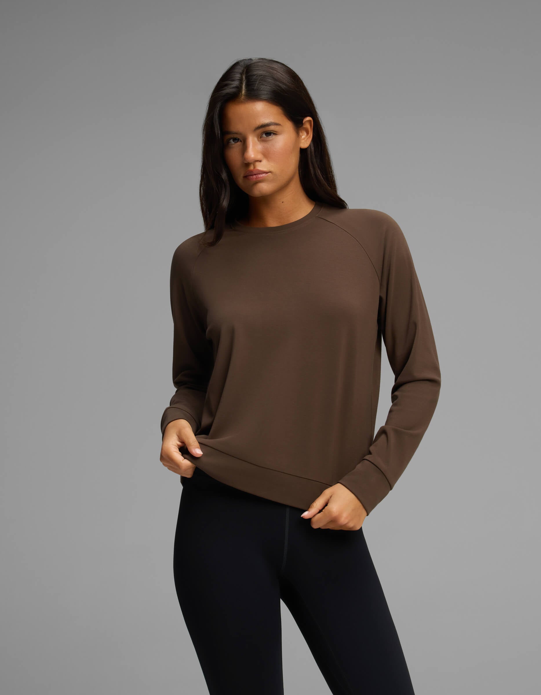A woman with long dark hair is wearing the Cozy Earth Women's Brushed Bamboo Pullover Crew in brown and black leggings, standing against a plain gray background.|Color:Espresso