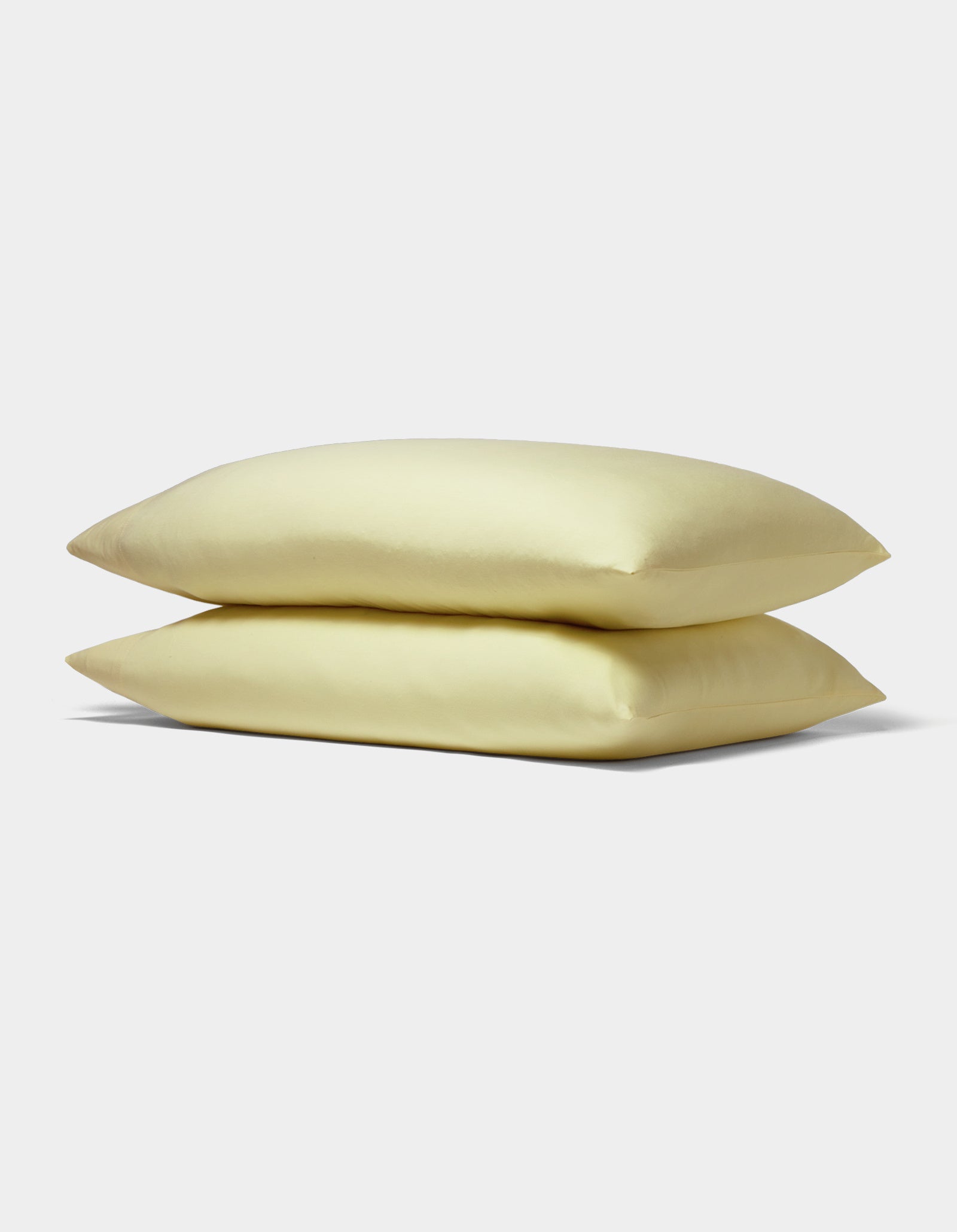 Two Bamboo Jersey Pillowcases from Cozy Earth, displayed in soft pale yellow and stacked neatly against a plain white background.|Color:Meringue