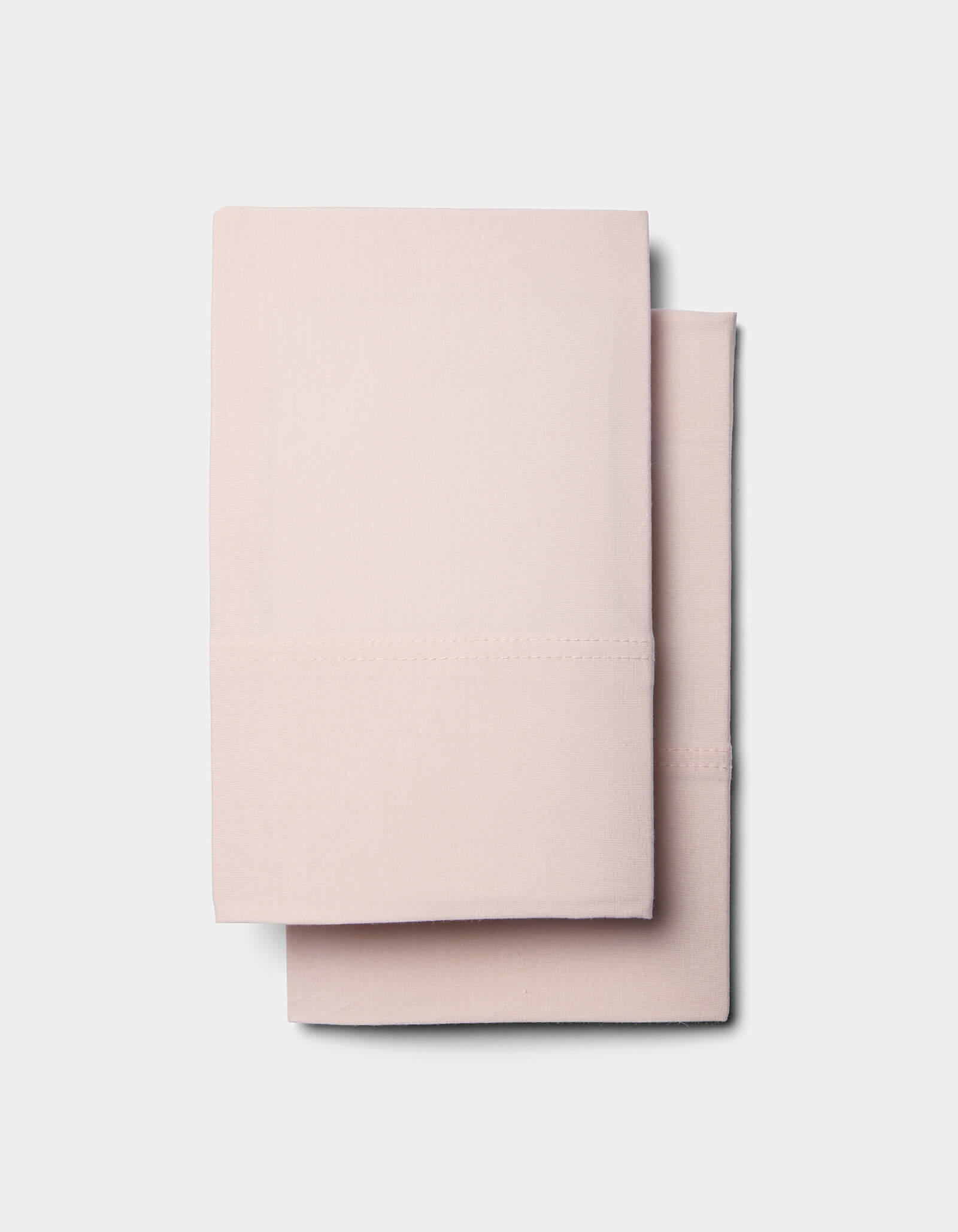 Two neatly folded, light pink Cozy Earth Bamboo Jersey Pillowcases stacked together against a plain white background.