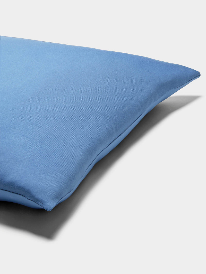 A close-up of a Cozy Earth Bamboo Jersey Pillowcase displays its smooth blue fabric against a plain white background.