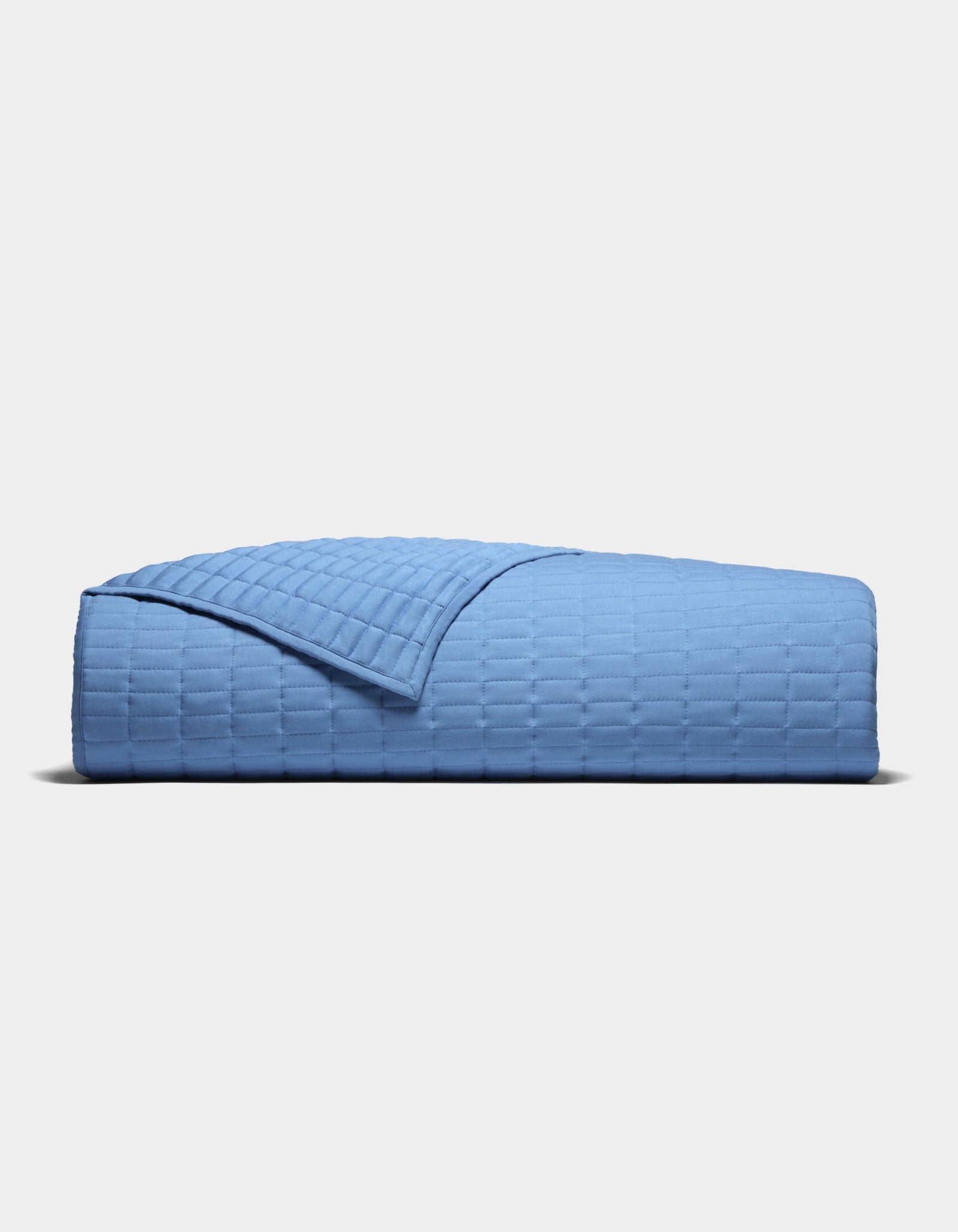 The Cozy Earth Bamboo Jersey Quilt, featuring a textured grid-like pattern in light blue, is neatly folded and displayed against a plain white background.|Color:Sailor