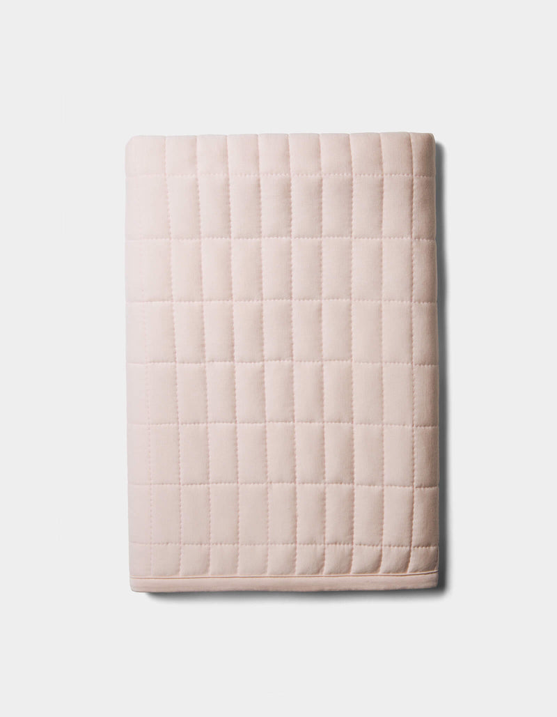 The Bamboo Jersey Quilted Shams by Cozy Earth, in light pink with a square grid pattern, are neatly folded and displayed on a plain white background.
