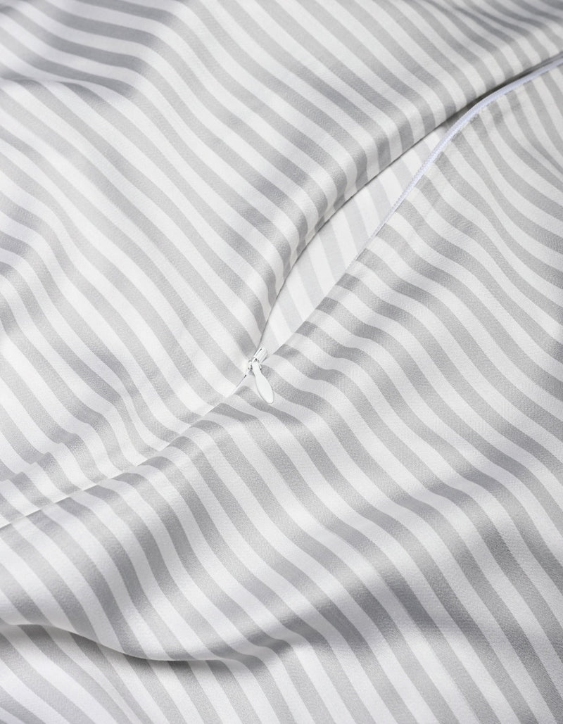 A close-up of the Cozy Earth Bamboo Duvet Cover in white and gray stripes, featuring a partially unzipped zipper that reveals its smooth, shiny texture and soft folds.