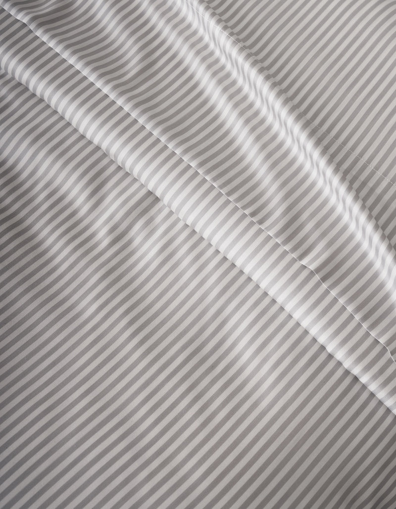 Close-up of Cozy Earth’s Bamboo Duvet Cover in light gray and white stripes, featuring a smooth texture with gentle folds and diagonal lines across the surface.