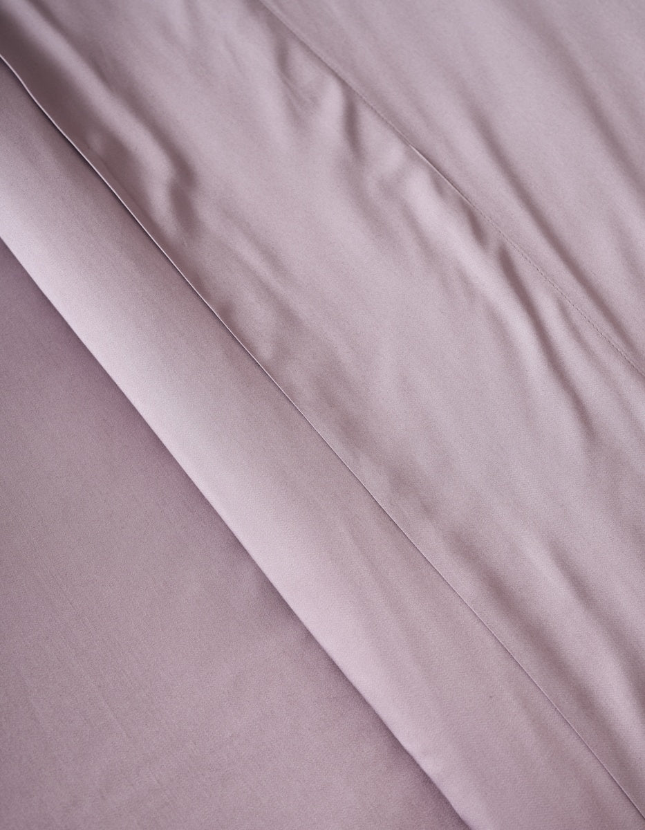 A close-up of the Cozy Earth Bamboo Duvet Cover in soft, light mauve shows visible folds and creases that create gentle shadows and enhance its textured appearance.