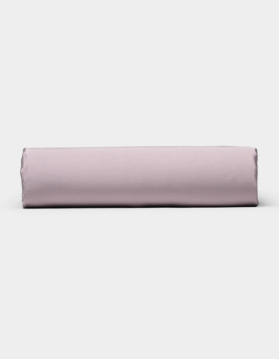 A neatly folded Cozy Earth Bamboo Fitted Sheet in light purple is positioned horizontally against a plain white background.