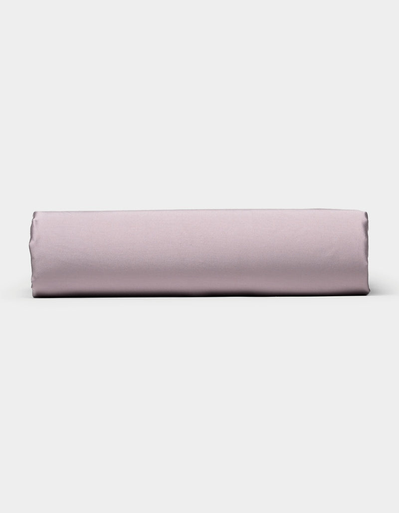 A neatly folded Cozy Earth Bamboo Fitted Sheet in light purple is positioned horizontally against a plain white background.
