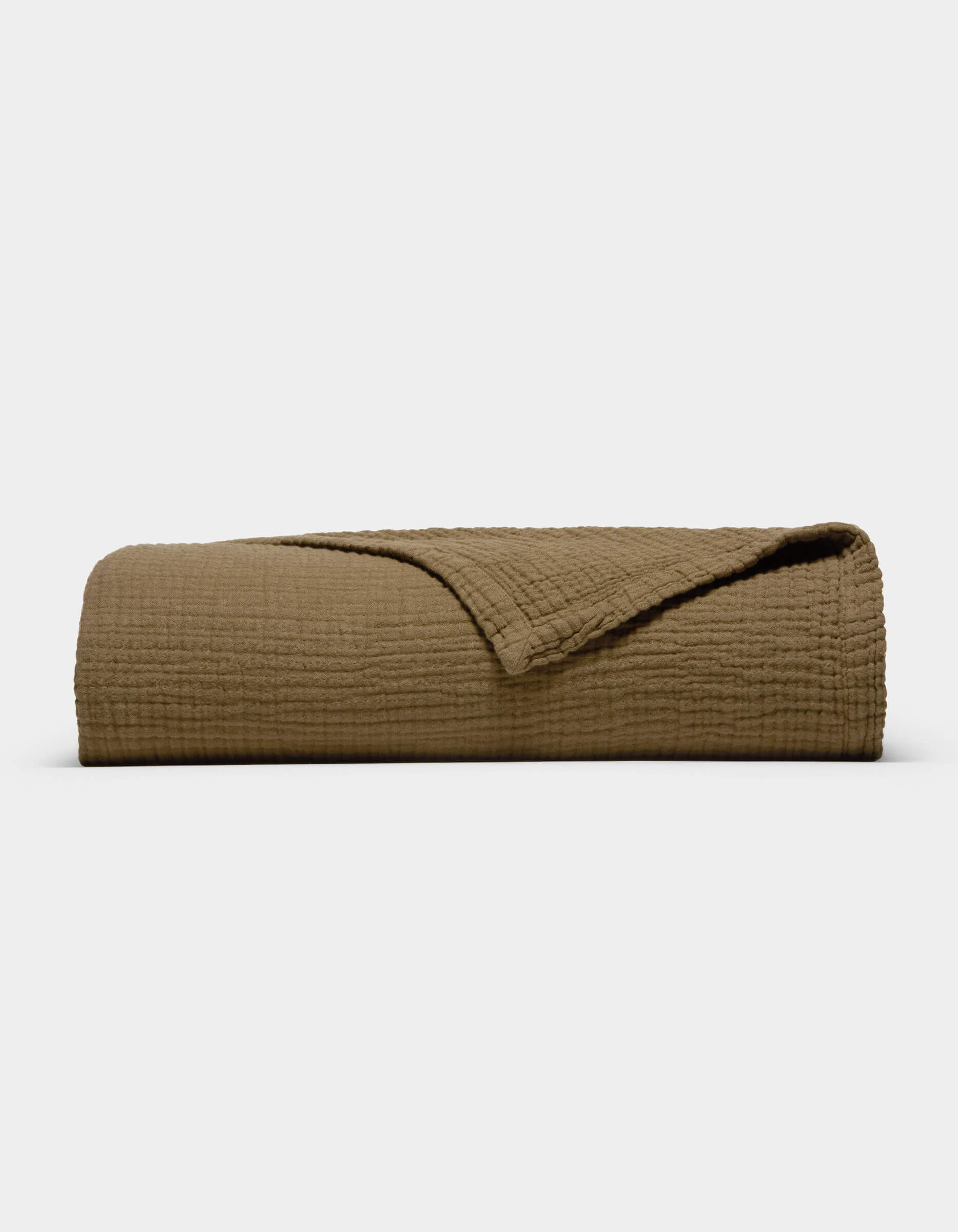 The Cozy Earth Cotton Gauze Blanket, featuring a folded, textured brown design with a corner turned back to reveal its soft inner side, is displayed against a plain white background.