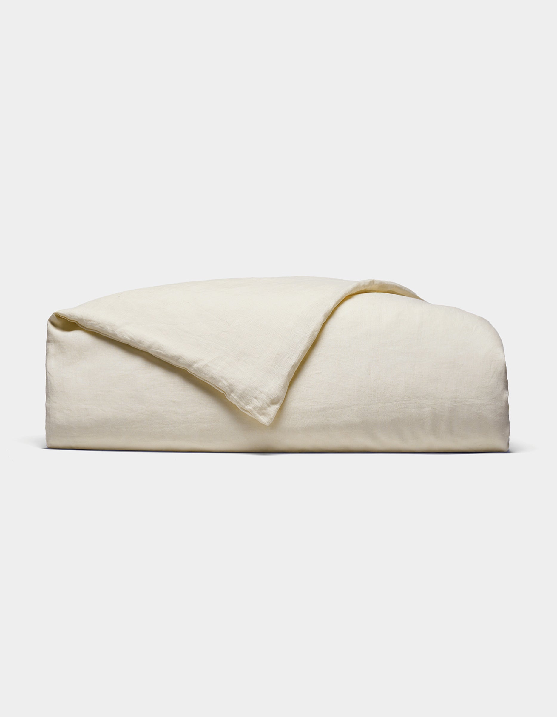 The Cozy Earth Linen Duvet Cover, in an off-white shade, is neatly folded against a white background. Its soft, slightly textured fabric is visible with one corner casually turned over.