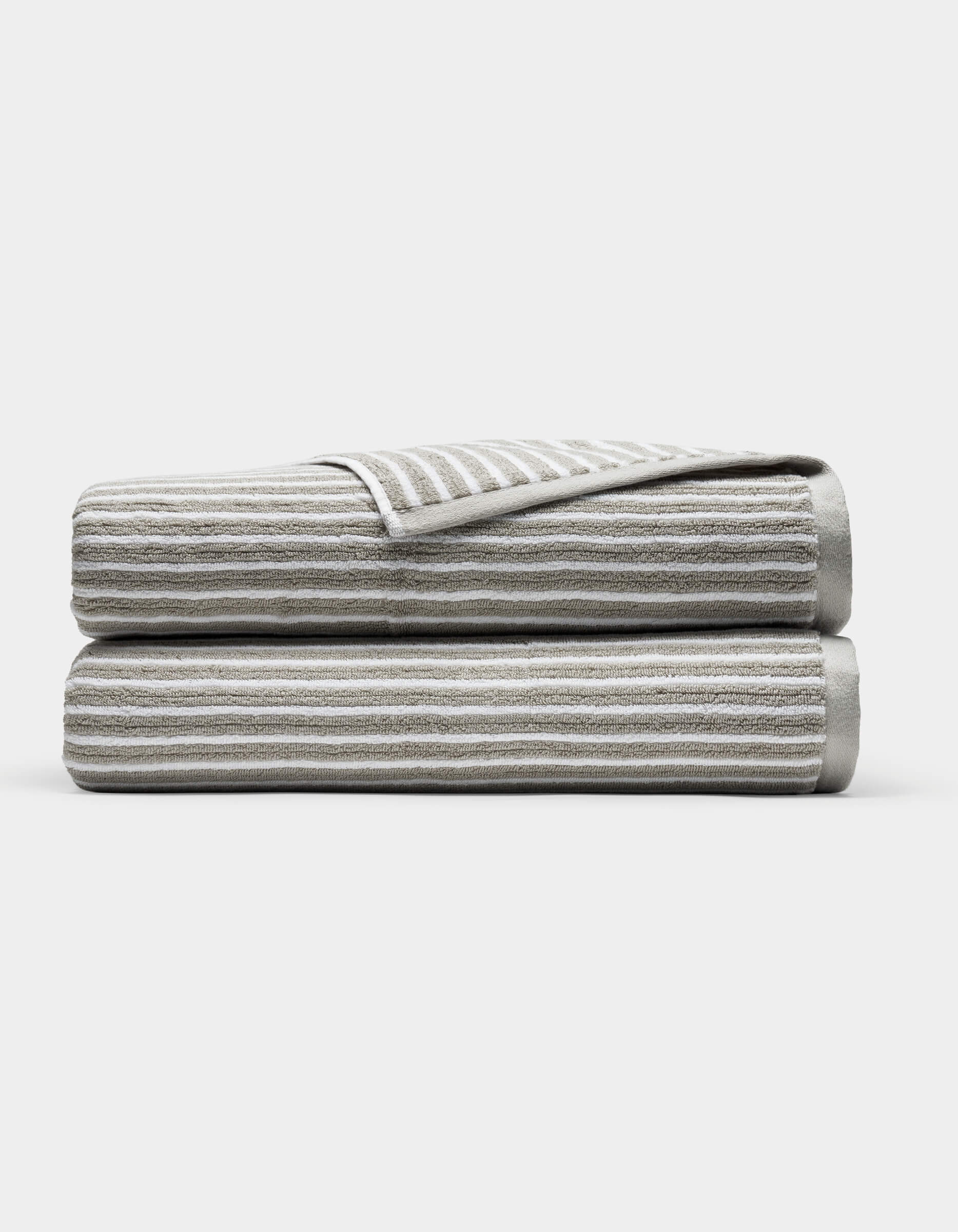 Two Cozy Earth Ribbed Terry Bath Sheets in gray and white stripes are folded and stacked on each other against a plain white background.|Color:Dew Stripe